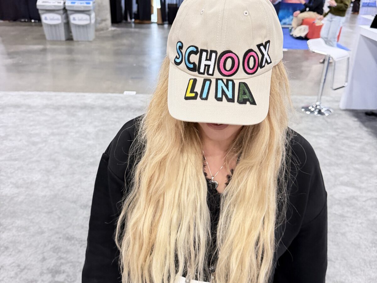 Guest wearing a custom cap finished with colorful chenille letter patches spelling the company name and her own name at a trade show